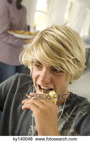 Portrait of a teen boy eating, woman in background View Large Photo Image Stock Photo - Portrait of a teen boy eating, woman in background. Fotosearch