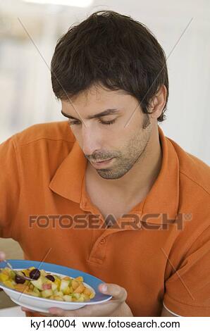 Portrait of a young man eating fruit salad View Large Photo Image Picture - Portrait of a young man eating fruit salad. Fotosearch