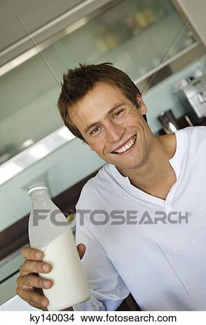Portrait of a young smiling man holding bottle of milk View Large Photo Image Picture - Portrait of a young smiling man holding bottle of milk. Fotosearch