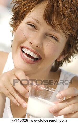 Portrait of a young smiling woman holding glass of milk View Large Photo Image Stock Photo - Portrait of a young smiling woman holding glass of milk. Fotosearch