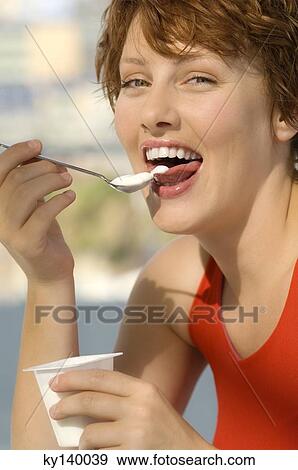 Portrait of a young smiling woman eating yogurt View Large Photo Image Stock Photo - Portrait of a young smiling woman eating yogurt. Fotosearch
