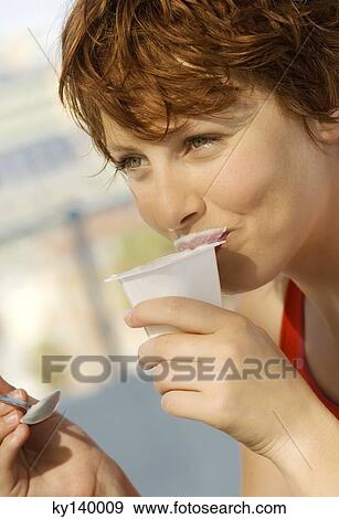 Portrait of a young woman eating yogurt View Large Photo Image Stock Photo - Portrait of a young woman eating yogurt. Fotosearch