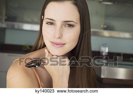 Portrait of a young woman looking at camera, holding spoon View Large Photo Image Stock Image - Portrait of a young woman looking at camera, holding spoon. Fotosearch