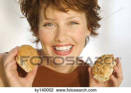 Stock Image - Portrait of smiling woman holding breads. Fotosearch