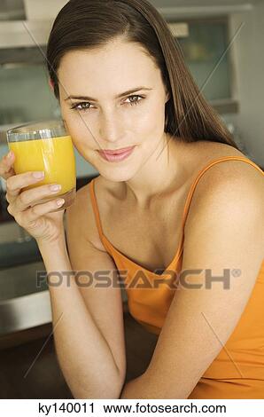 Young woman holding glass of orange juice View Large Photo Image Stock Image - Young woman holding glass of orange juice. Fotosearch