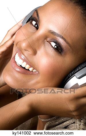 Stock Image - Portrait of a young woman, listening to music with headphones. Fotosearch