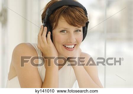Stock Image - Portrait of a young woman, listening to music with headphones. Fotosearch