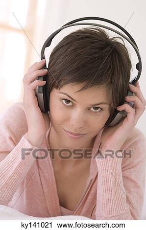 Stock Image - Portrait of a young woman, listening to music with headphones. Fotosearch