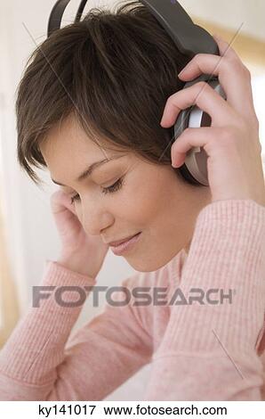 Stock Photo - Portrait of a young woman, listening to music with headphones. Fotosearch