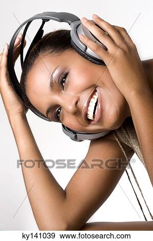 Stock Photo - Portrait of a young woman, listening to music with headphones. Fotosearch