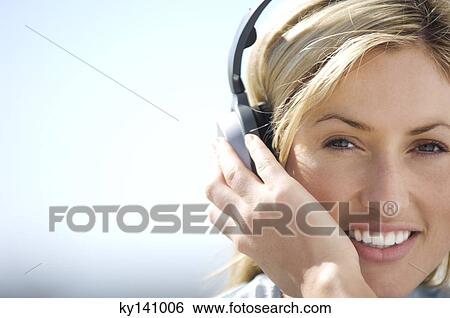 Stock Photograph - Portrait of a young woman, listening to music with headphones. Fotosearch