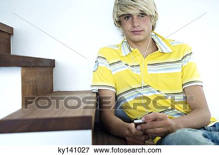 Teenage boy listening to MP3 player, sitting on stairs View Large Photo Image Stock Photo - Teenage boy listening to MP3 player, sitting on stairs. Fotosearch