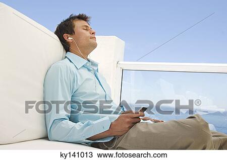 Young man listening to MP3 player View Large Photo Image Stock Image - Young man listening to MP3 player. Fotosearch