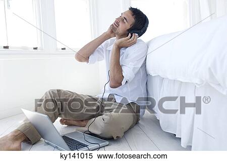Young man listening to music with laptop View Large Photo Image Stock Photography - Young man listening to music with laptop. Fotosearch
