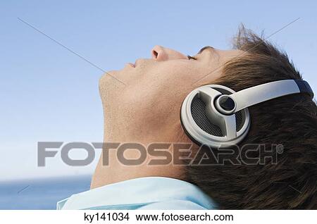 Young man listening to music with headphones View Large Photo Image Picture - Young man listening to music with headphones. Fotosearch