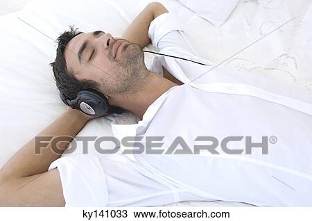 Young man listening to music with headphones View Large Photo Image Stock Image - Young man listening to music with headphones. Fotosearch