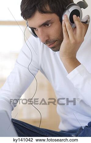 Young man listening to music with headphones View Large Photo Image Stock Image - Young man listening to music with headphones. Fotosearch