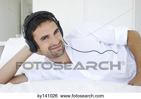 Young man listening to music with headphones View Large Photo Image Stock Photograph - Young man listening to music with headphones. Fotosearch