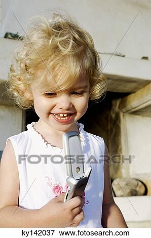 Little girl holding mobile phone, outdoors View Large Photo Image Stock Photo - Little girl holding mobile phone, outdoors. Fotosearch