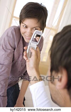 Man photographing young woman with camera phone View Large Photo Image Stock Photography - Man photographing young woman with camera phone. Fotosearch