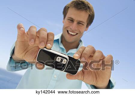 Portrait of a man using camera phone View Large Photo Image Picture - Portrait of a man using camera phone. Fotosearch