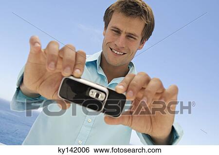 Stock Photograph - Portrait of a man using camera phone. Fotosearch
