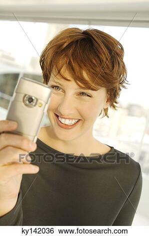 Portrait of a smiling woman using camera phone View Large Photo Image Stock Photograph - Portrait of a smiling woman using camera phone. Fotosearch