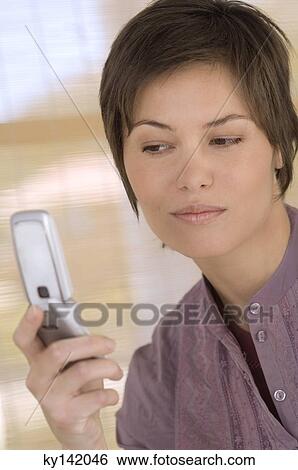 Portrait of a young woman using mobile phone View Large Photo Image Stock Photograph - Portrait of a young woman using mobile phone. Fotosearch