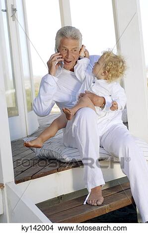 Senior man using mobile phone, with little boy View Large Photo Image Picture - Senior man using mobile phone, with little boy. Fotosearch