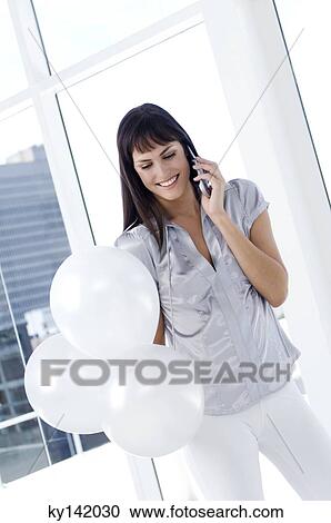 Smiling woman phoning, holding white balloons View Large Photo Image Stock Image - Smiling woman phoning, holding white balloons. Fotosearch