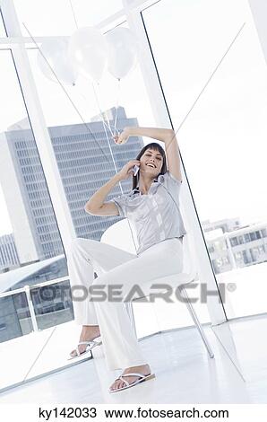 Smiling woman phoning, holding white balloons View Large Photo Image Stock Image - Smiling woman phoning, holding white balloons. Fotosearch