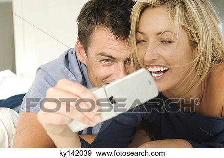 Young couple in bed, using mobile phone View Large Photo Image Stock Photo - Young couple in bed, using mobile phone. Fotosearch