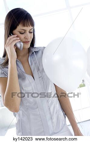 Young woman phoning, holding white balloons View Large Photo Image Stock Image - Young woman phoning, holding white balloons. Fotosearch