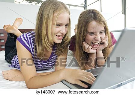 2 teen girls lying on bed using laptop View Large Photo Image Stock Photo - 2 teen girls lying on bed using laptop. Fotosearch