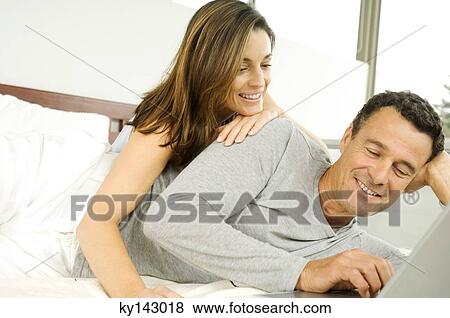 Couple in bed, using laptop View Large Photo Image Stock Photo - Couple in bed, using laptop. Fotosearch