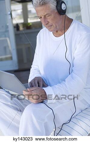 Man with headphones using laptop View Large Photo Image Stock Image - Man with headphones using laptop. Fotosearch