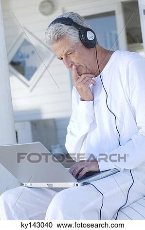 Man with headphones using laptop View Large Photo Image Stock Image - Man with headphones using laptop. Fotosearch