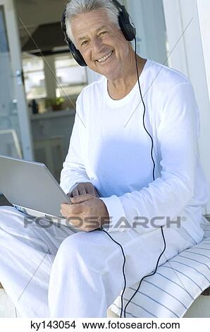 Smiling man with headphones using laptop View Large Photo Image Picture - Smiling man with headphones using laptop. Fotosearch