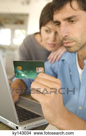 Picture - Young couple using credit card on internet. Fotosearch