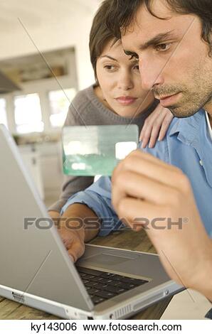 Stock Photograph - Young couple using credit card on internet. Fotosearch