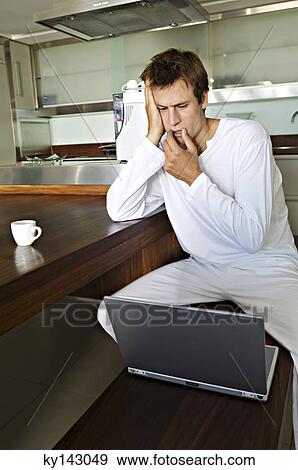 Young man using laptop in kitchen View Large Photo Image Stock Photo - Young man using laptop in kitchen. Fotosearch