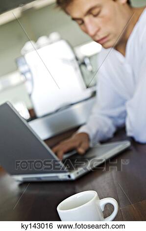 Young man using laptop in kitchen View Large Photo Image Stock Photograph - Young man using laptop in kitchen. Fotosearch