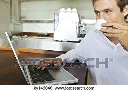 Young man using laptop in kitchen View Large Photo Image Stock Photograph - Young man using laptop in kitchen. Fotosearch