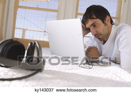 Young man using laptop View Large Photo Image Stock Photo - Young man using laptop. Fotosearch
