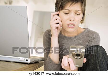 Young woman phoning, holding digital camera View Large Photo Image Stock Photo - Young woman phoning, holding digital camera. Fotosearch