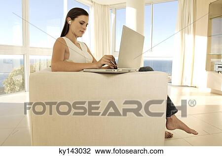 Young woman using laptop in living-room View Large Photo Image Stock Image - Young woman using laptop in living-room. Fotosearch