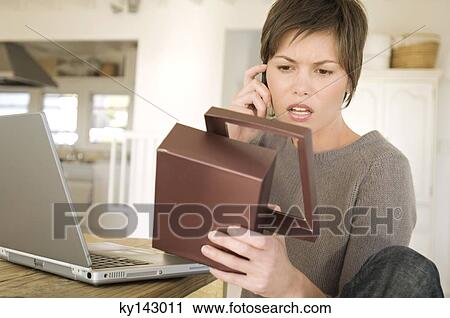 Young woman with laptop, phoning, holding box View Large Photo Image Stock Image - Young woman with laptop, phoning, holding box. Fotosearch