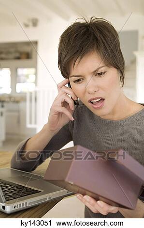 Young woman with laptop, phoning, holding box View Large Photo Image Stock Image - Young woman with laptop, phoning, holding box. Fotosearch