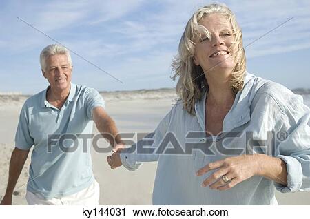 Couple holding hands, walking on the beach View Large Photo Image Stock Image - Couple holding hands, walking on the beach. Fotosearch