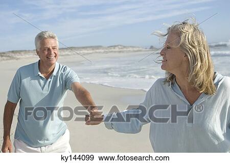 Couple holding hands, walking on the beach View Large Photo Image Stock Photo - Couple holding hands, walking on the beach. Fotosearch